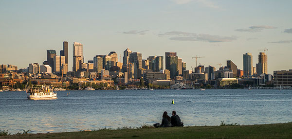 People siting in a park looking at the Seattle skyline.
