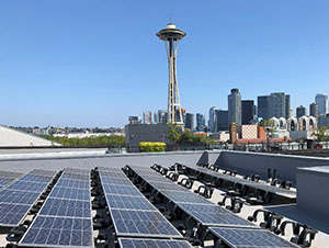 Solar panels on a roof in Seattle with the Space Needle in the distance.