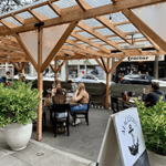 A sidewalk cafe with a couple of people sitting at a table.
