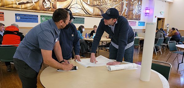 Inspectors standing at a table answering a customer's question at the 2023 home fair.