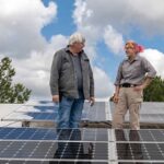 To people standing on a roof with solar panels.